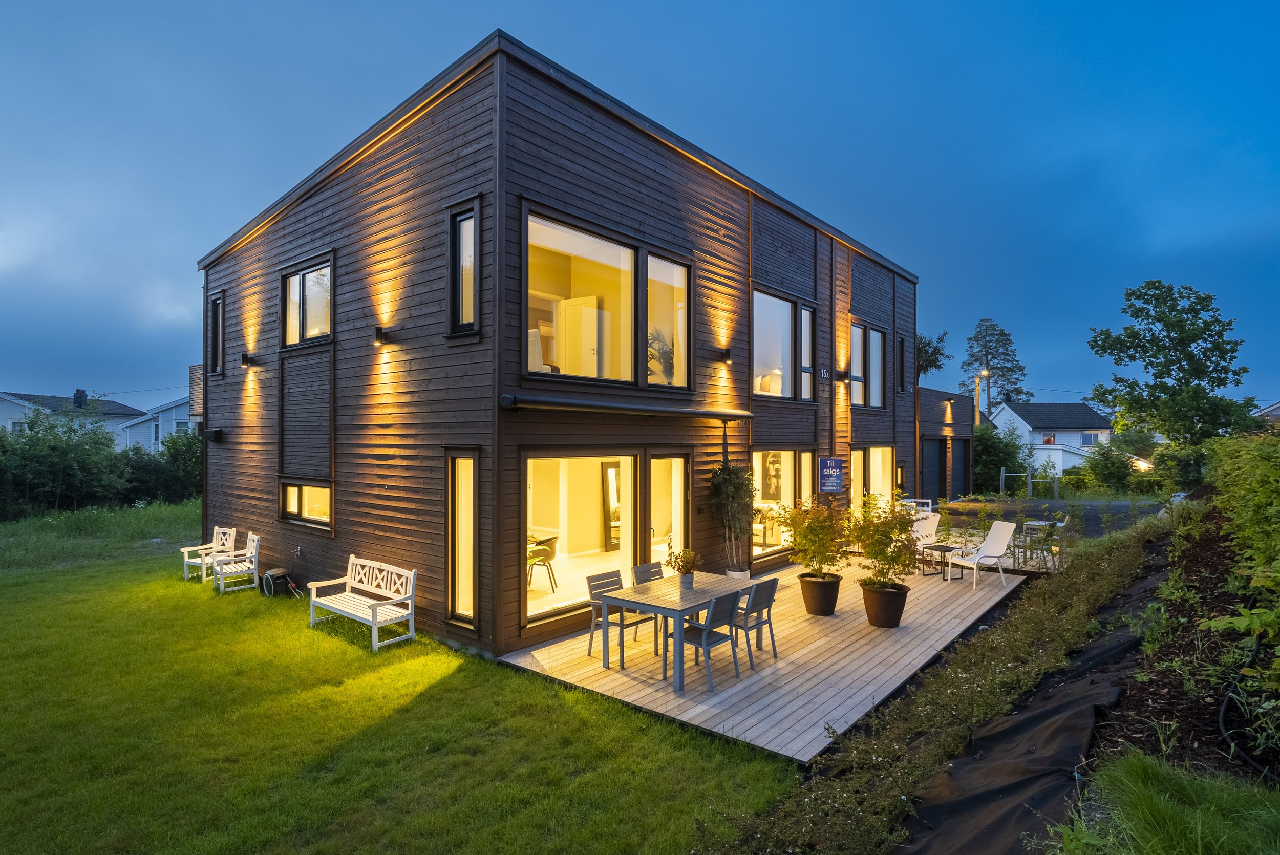 Ringshaughøyden 15A i kveldslys, med opplyst terrasse og ferdig uteområde